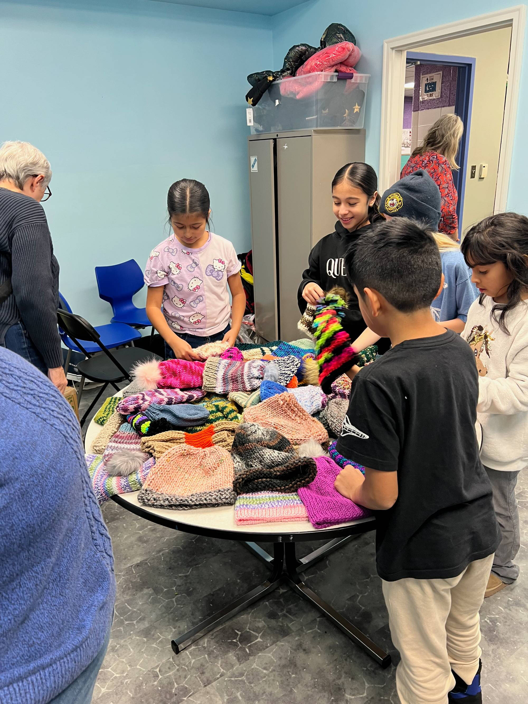 Students choosing their knitted items from a table.